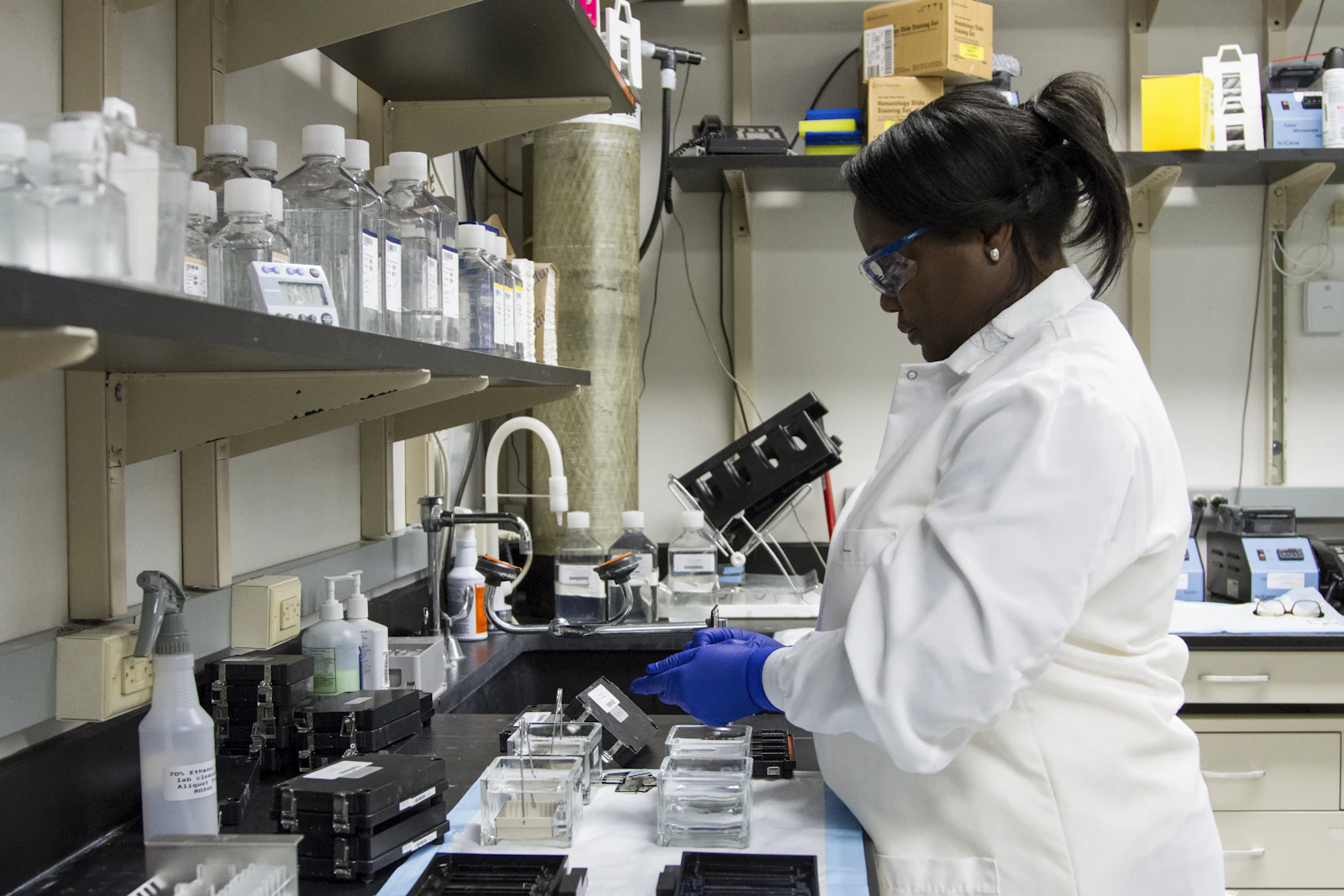 A pharmacist in a white coat working at a laboratory bench